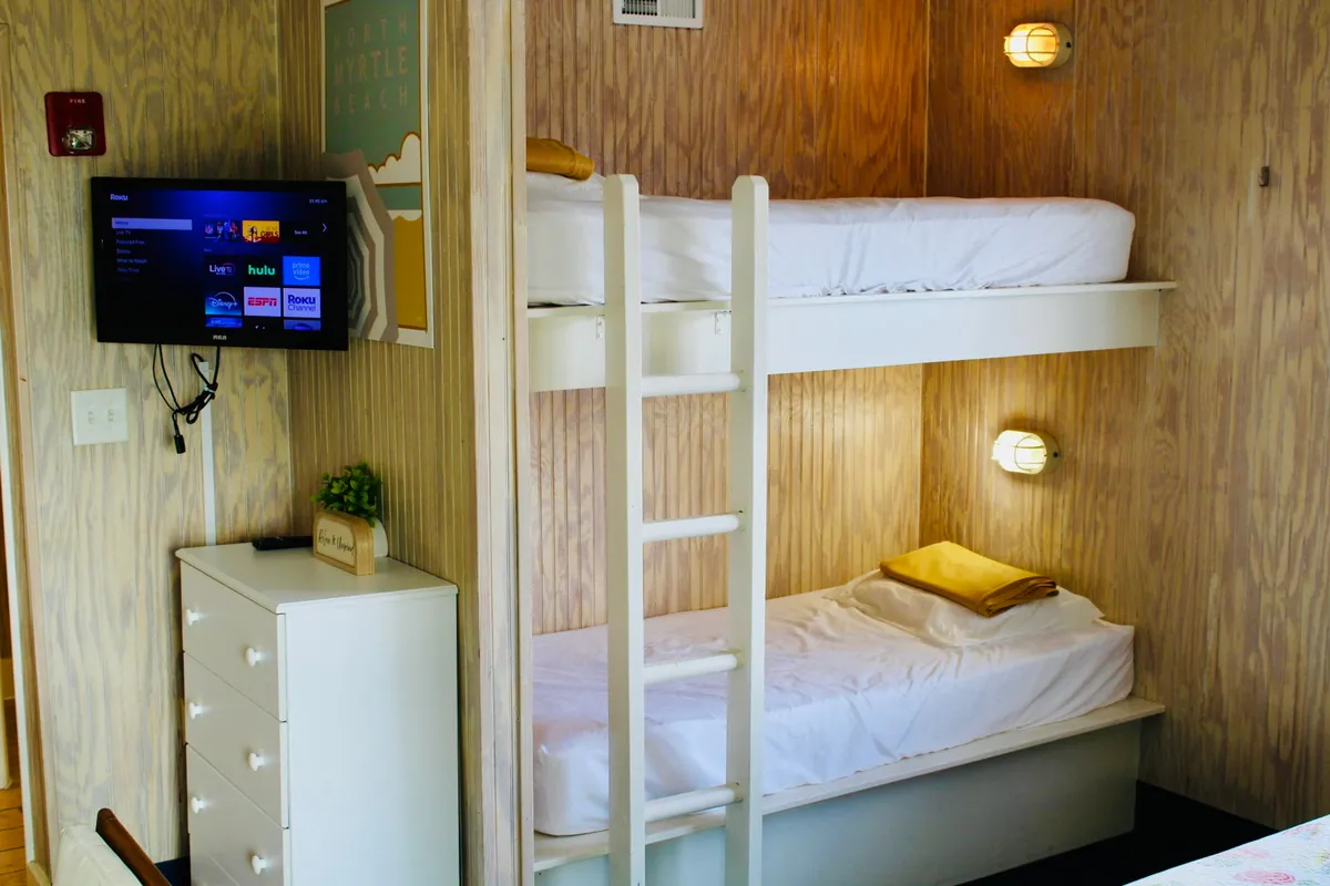 A playful, family-friendly room with cozy bunk beds, a television, and cheerful wall art. The space exudes relaxation and comfort, ideal for unwinding after a day at the beach or Main Street.